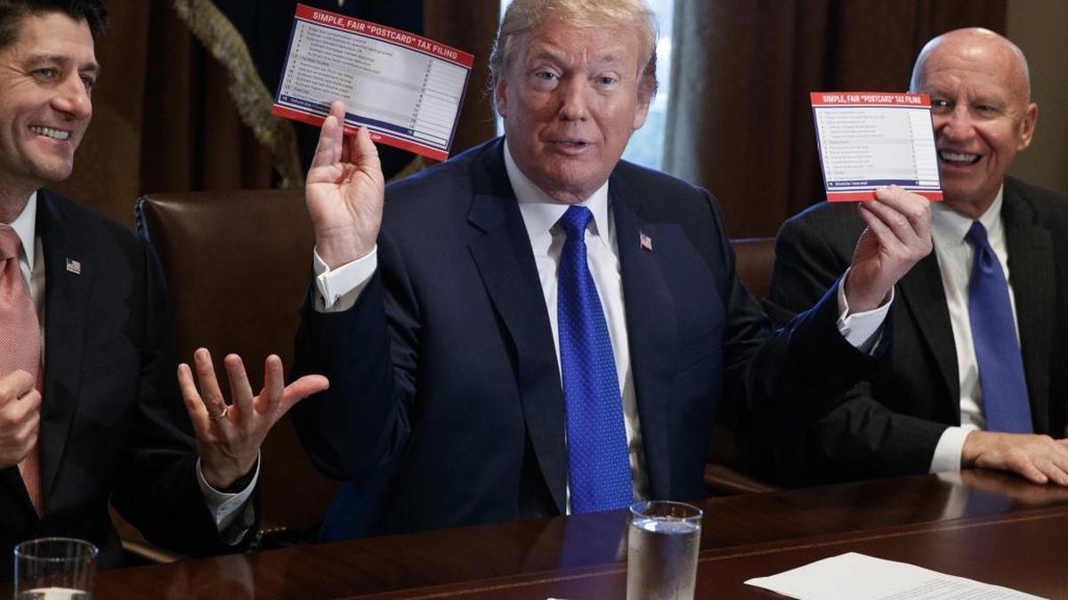 President Donald Trump holds an example of what a new tax form may look like during a meeting on tax policy with Republican lawmakers including House Speaker Paul Ryan of Wisconsin and chairman of the House Ways and Means Committee Rep. Kevin Brady, R-Texas, right, in the Cabinet Room of the White House on Nov. 2.