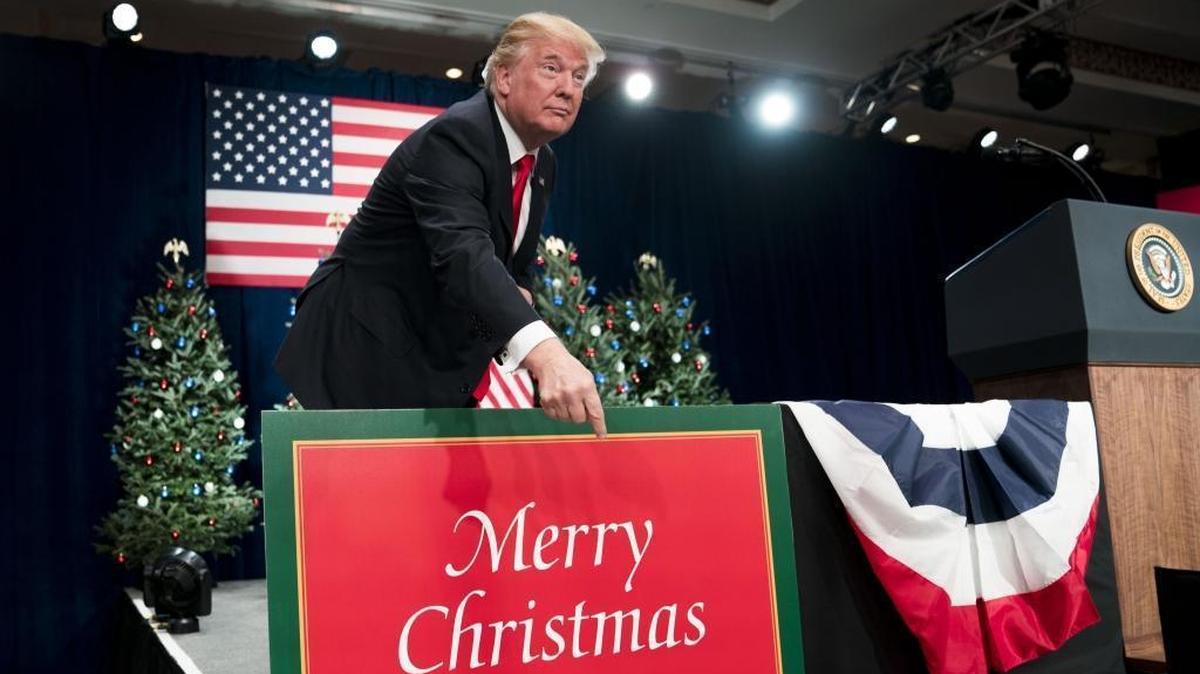 President Donald Trump points to a “Merry Christmas” sign as he arrives to make remarks on tax reform at the St. Charles Convention Center in St. Charles, Mo., Nov. 29, 2017.