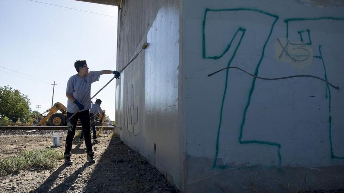 A high school student paints over graffiti in 2014 on Florin Road, one of 43 newly designated “Opportunity Zones” in Sacramento County. The federal program offers capital gains breaks for investment in “distressed communities.”