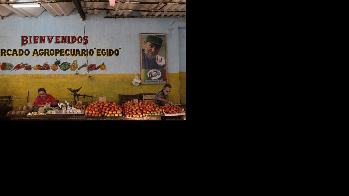 
With a framed image of revolutionary leader Fidel Castro on the wall, a vendor organizes his tomatoes at an open-air market in Havana, Cuba, last year. As more and more islanders go into business for themselves under President Raul Castro’s economic reforms, the ethos of capitalism is increasingly seeping into Cuban daily life. 

