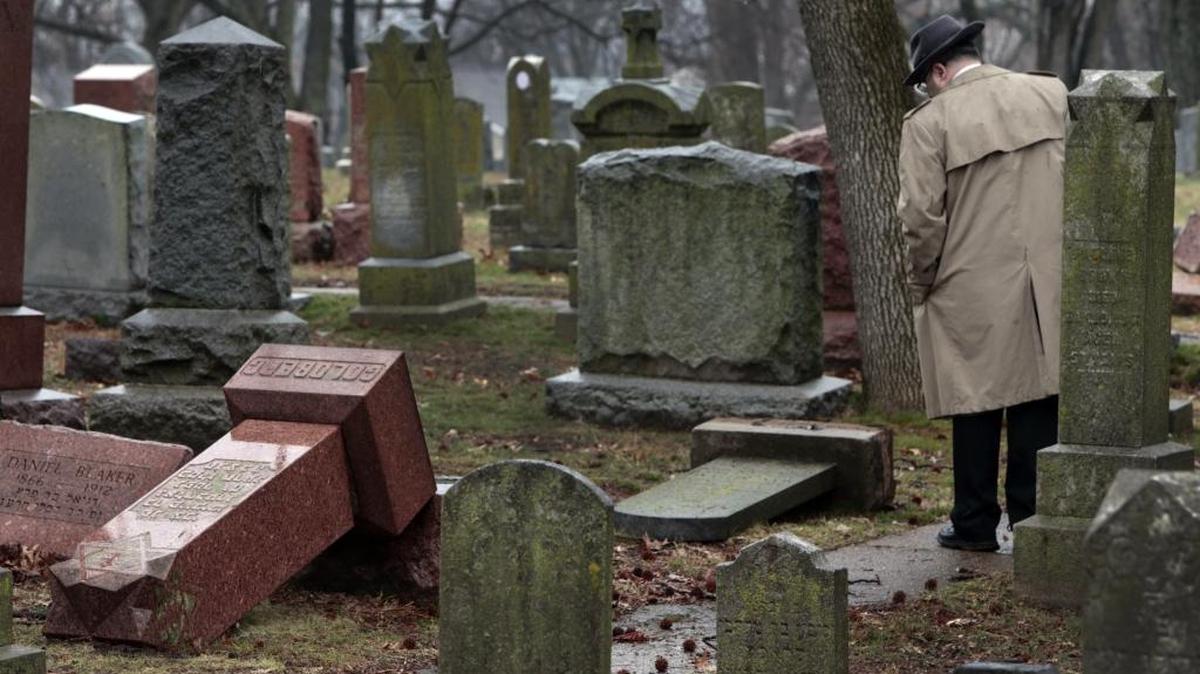 People walk through toppled graves at Chesed Shel Emeth Cemetery in University City, Mo., on Feb. 21. Authorities in Missouri are investigating after dozens of headstones were tipped over at the Jewish cemetery near St. Louis.