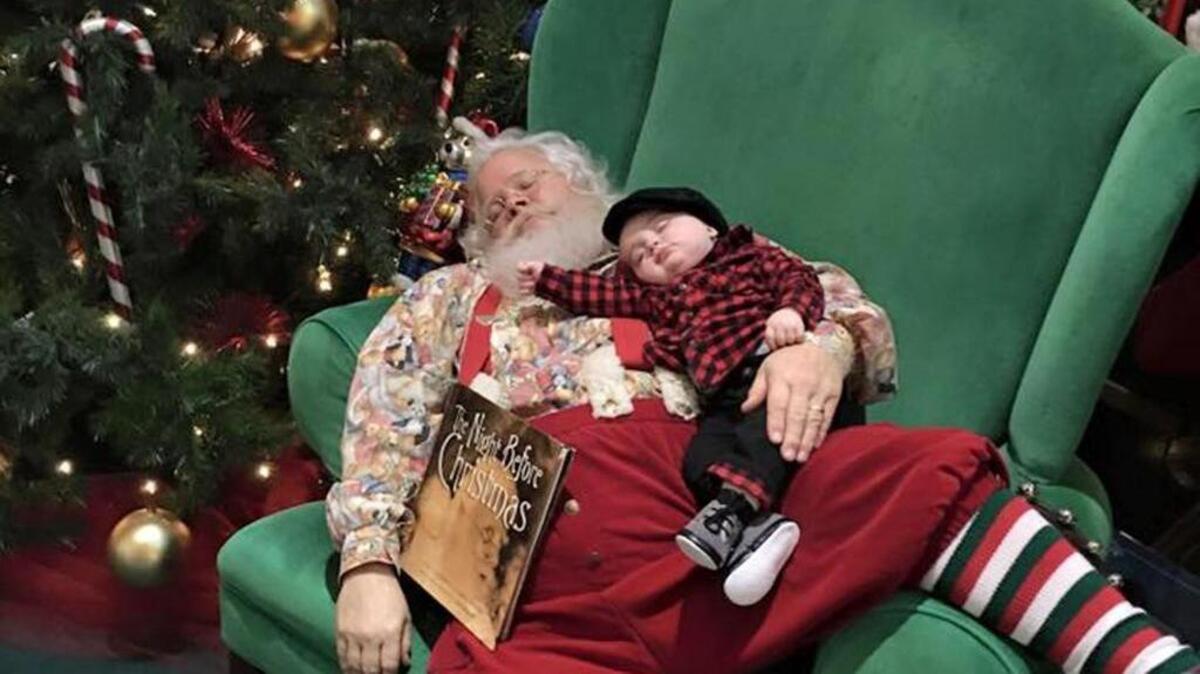 The holidays can be exhausting, even for Santa, shown here posing with a sleeping child in 2015 for a parent in an Evansville, Ind., shopping mall.