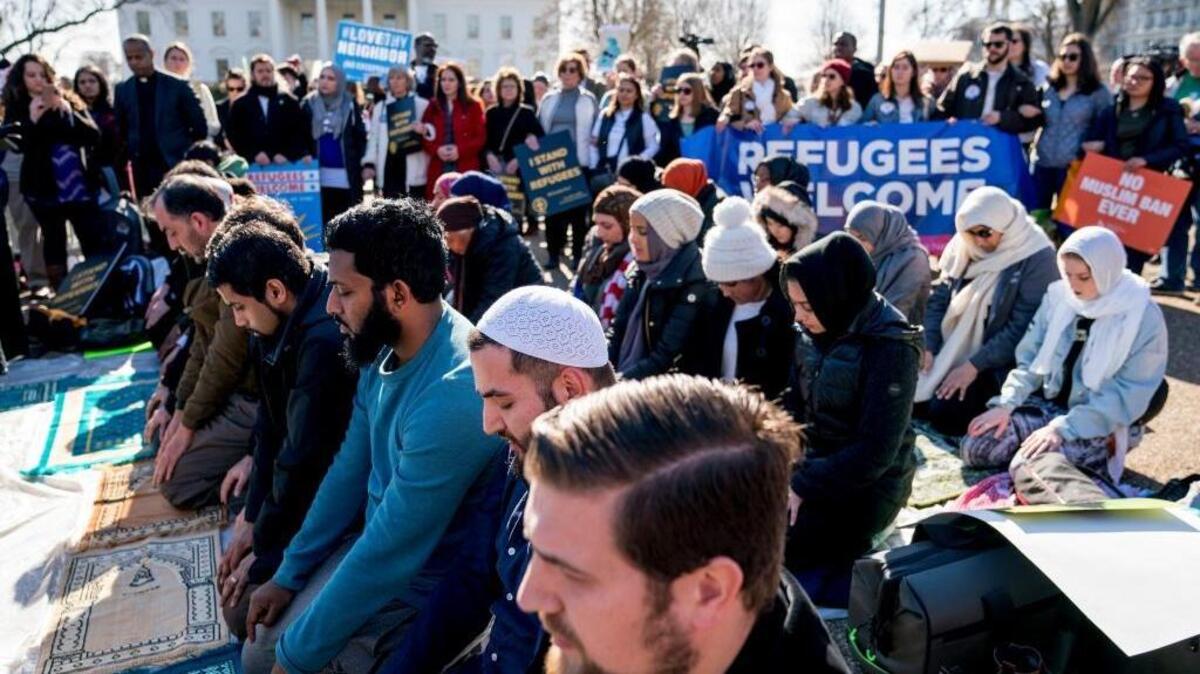 Supporters surround a group who perform the Islamic midday prayer outside the White House in Washington on Saturday during a rally on the one-year anniversary of the Trump Administration’s first partial travel ban on citizens from Muslim majority countries. The U.S. Supreme Court has granted review in the latest challenge to the latest version of Trump’s ban.