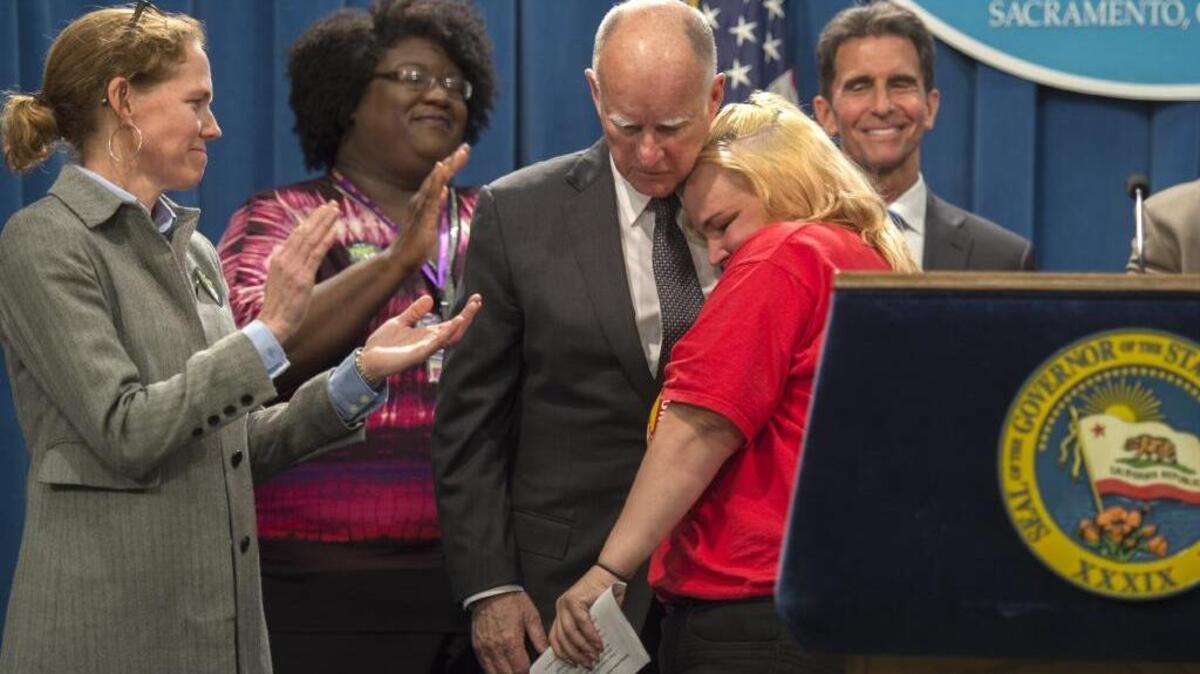 After Gov. Jerry Brown announces a landmark agreement to raise the minimum wage to $15 an hour, he hugs an emotional Burger King employee Holly Diaz, who described her hardship of trying to raise her 5-month-old son and stay at her job that she has held for the past nine years on minimum wages.
