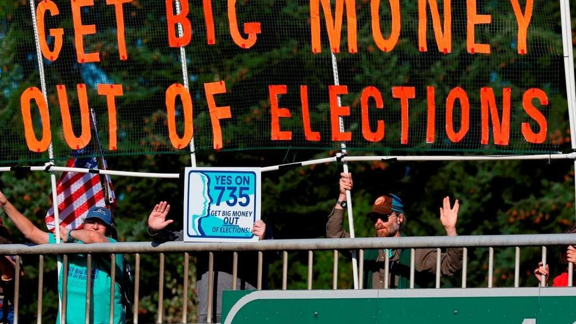 Supporters of a 2016 Washington state ballot initiative calling on the state’s congressional delegation to oppose the U.S. Supreme Court’s “Citizens United” ruling unfurl a banner over the freeway near Lacey, Wash., on Sept. 22, 2016. (AP Photo/Ted S. Warren, File)