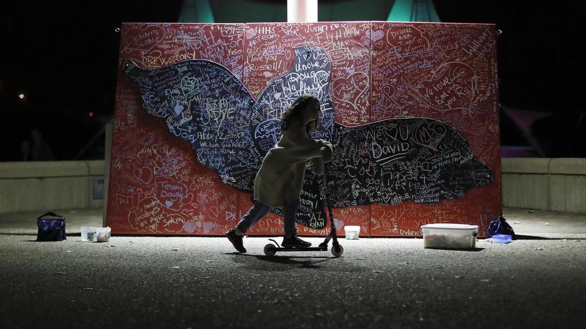 A child plays beside a message board filled with notes for loved ones who took their own lives during an event organized by the Cincinnati chapter of the American Foundation for Suicide Prevention.