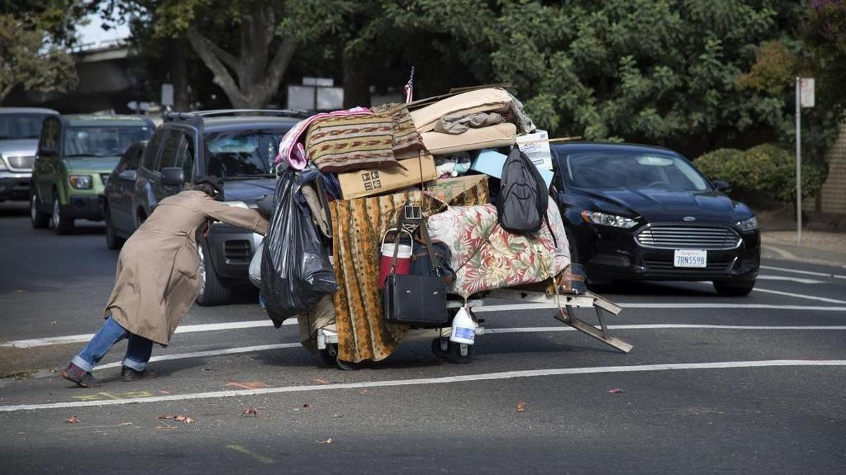 A homeless man pulls a cart with his belongings across X Street near 16th Street on Friday, September 28, 2017 in Sacramento.