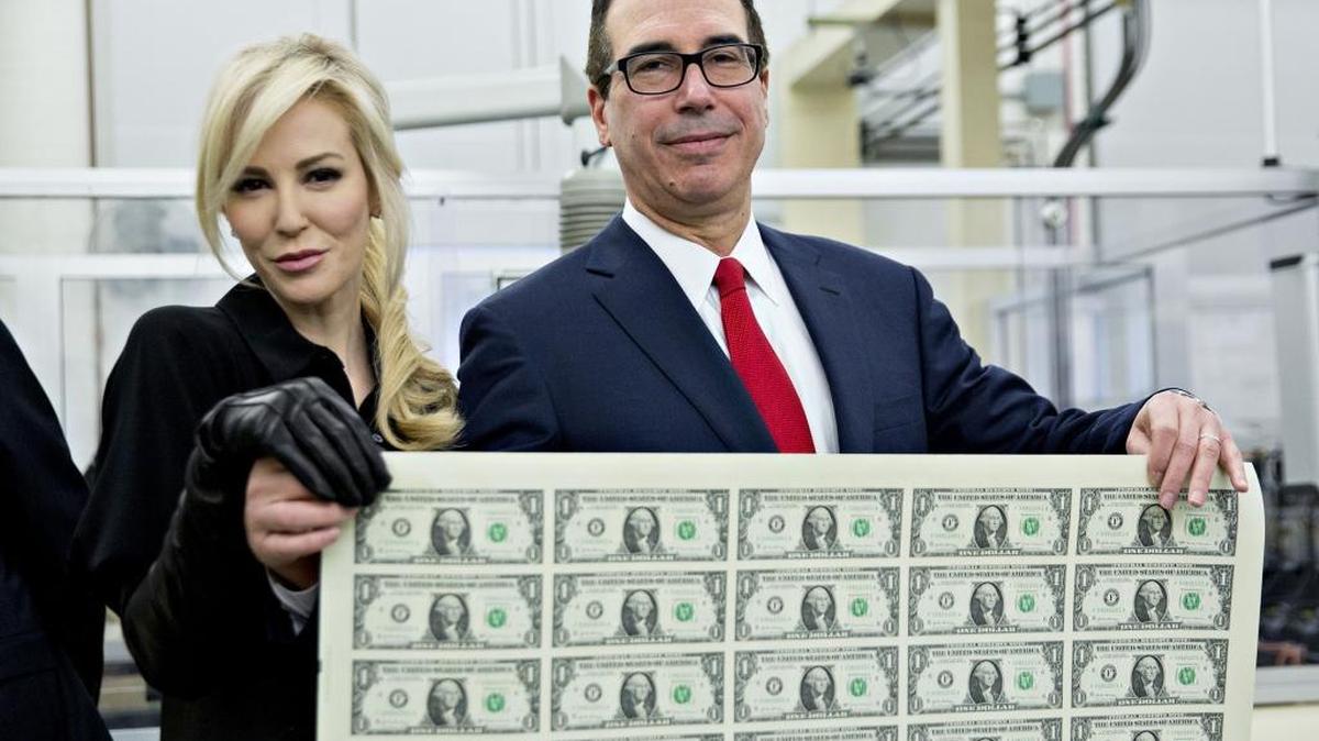 Treasury Secretary Steven Mnuchin, right, and wife, Louise Linton, hold an uncut sheet of $1 dollar notes with his signature. Mnuchin, a former Goldman Sachs executive, is one of many millionaires and billionaires in Trump’s administration.
