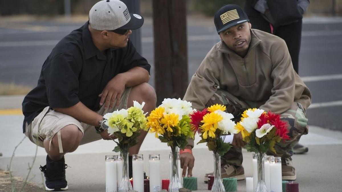 Steven Stanford, left, and Damon Flenaugh kneel by flowers in memorium of Flenaugh’s brother, Dazion, a mentally ill man shot last year by Sacramento police.
