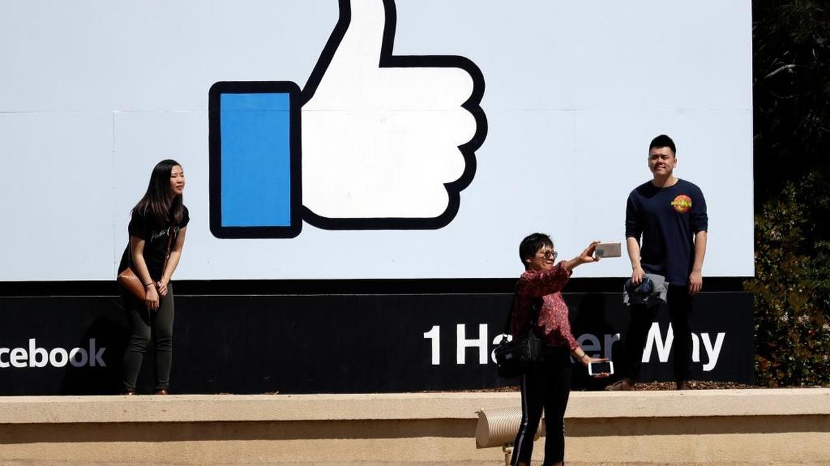 Visitors take photos in front of the Facebook logo at the company's headquarters Wednesday, March 28, 2018, in Menlo Park, Calif. Despite the rise of social networks, studies show an increase in loneliness. (AP Photo/Marcio Jose Sanchez)