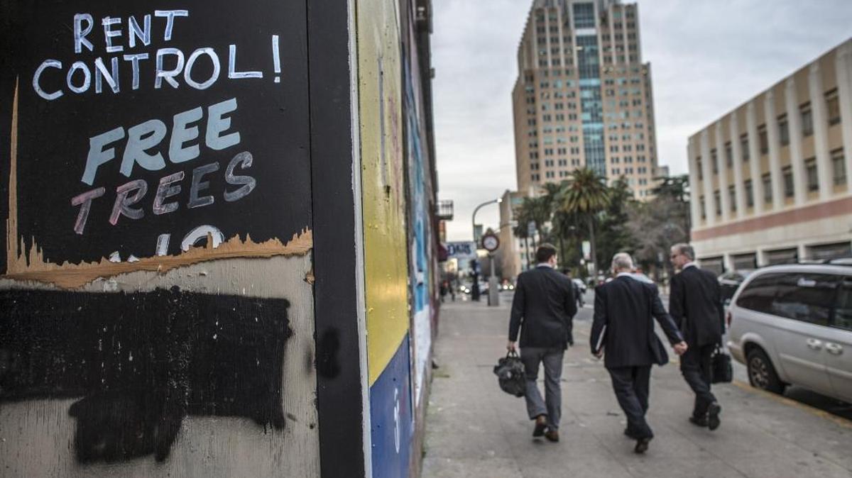Pedestrians walk past a vacant building with ‘Rent Control!’ graffiti on J Street between 10th and 11th in Sacramento, Calif., on Monday, Jan. 29, 2018.
