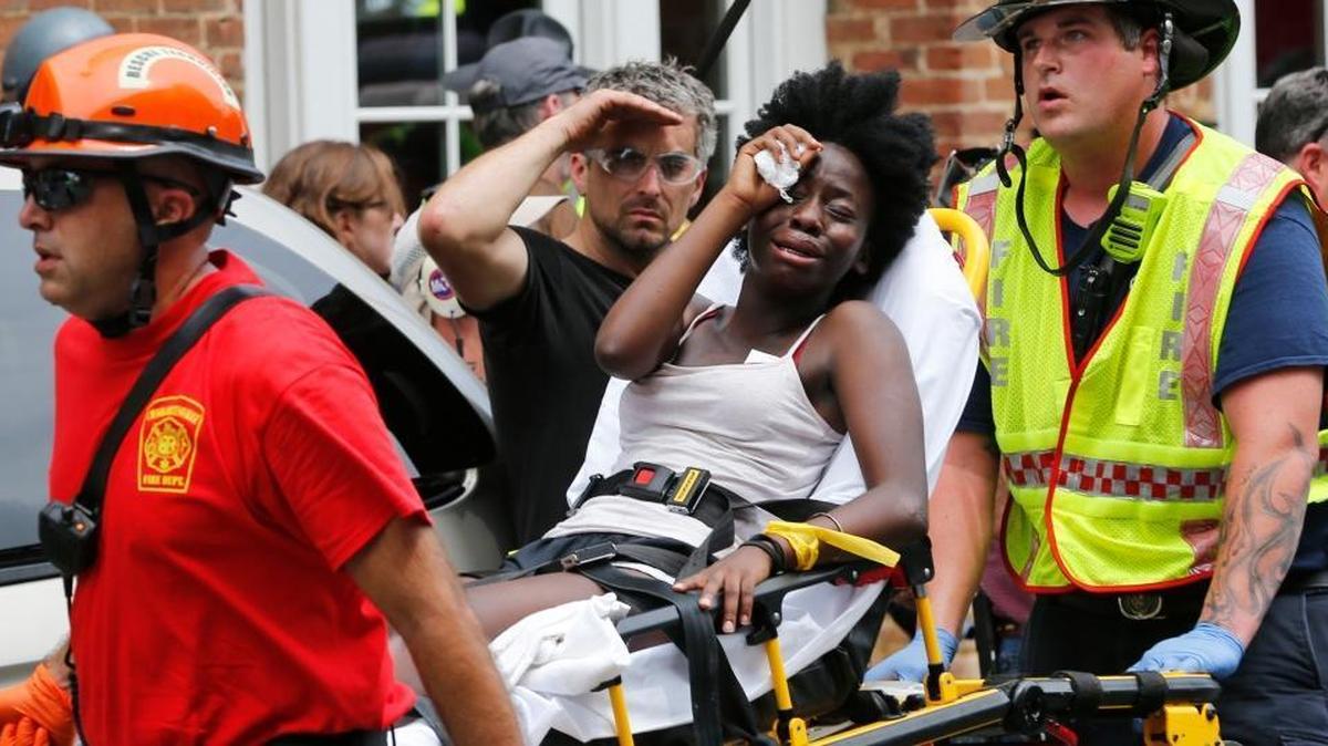 Rescue personnel help an injured woman after a car ran into a large group of protesters after an white nationalist rally in Charlottesville, Va., Saturday, Aug. 12, 2017.