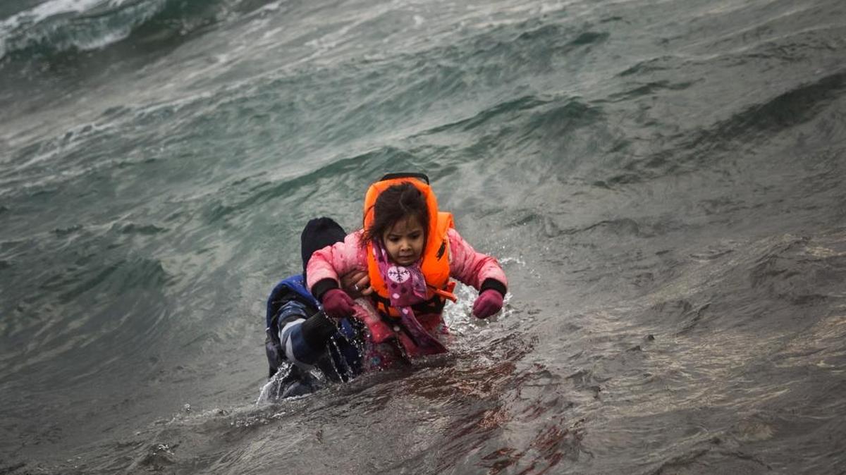A refugee carries a child from a dinghy in 2016 after crossing part of the Aegean Sea from Turkey to the Greek island of Lesbos. More than a million people reached Europe in 2015 in the continent's largest refugee influx since the end of World War II. Nearly 3,800 people are estimated to have drowned in the Mediterranean last year, making the journey to Greece or Italy in unseaworthy vessels packed far beyond capacity. (AP Photo/Santi Palacios)