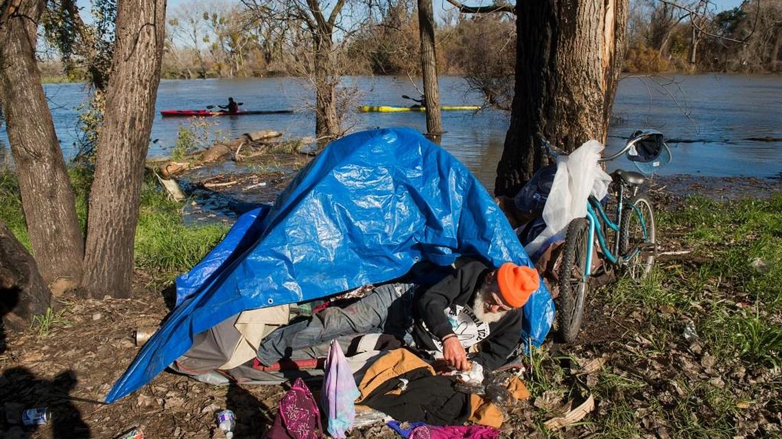 A homeless man camps near the American River in 2016. Sacramento’s city and county government are at odds over whether it will be more effective to jointly leverage resources or deploy more law enforcement along the river parkway.