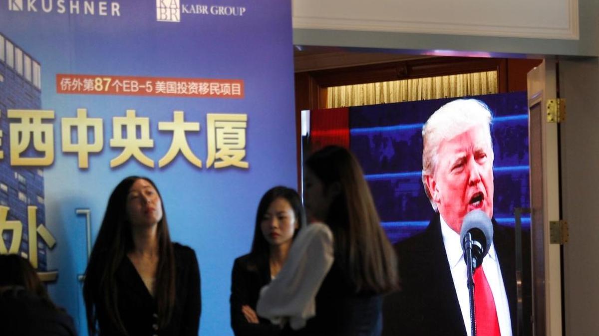A projector screen shows a footage of U.S. President Donald Trump as workers wait for investors at a reception desk during an event promoting EB-5 investment in a Kushner Companies development at a hotel in Shanghai, China, on Sunday. The sister of President Trump's son-in-law, Jared Kushner, has been courting Chinese investors using a much-criticized federal visa program that provides a path toward obtaining green cards.