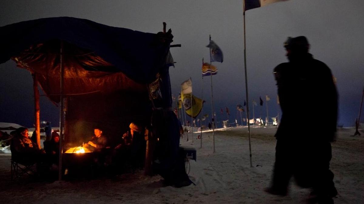 People sit around a campfire at the Oceti Sakowin camp where thousands have gathered to protest the Dakota Access oil pipeline near Cannon Ball, N.D. The pipeline is designed to carry oil from North Dakota to Illinois. The Standing Rock Sioux tribe says it will harm drinking water and sacred sites.