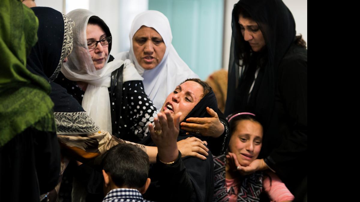 
Malala Rafi, center, and her daughter Mariam, 13, right, are comforted by community members during a funeral for her husband, Mustafa Rafi, at the Muslim Mosque Association on Tuesday. 
