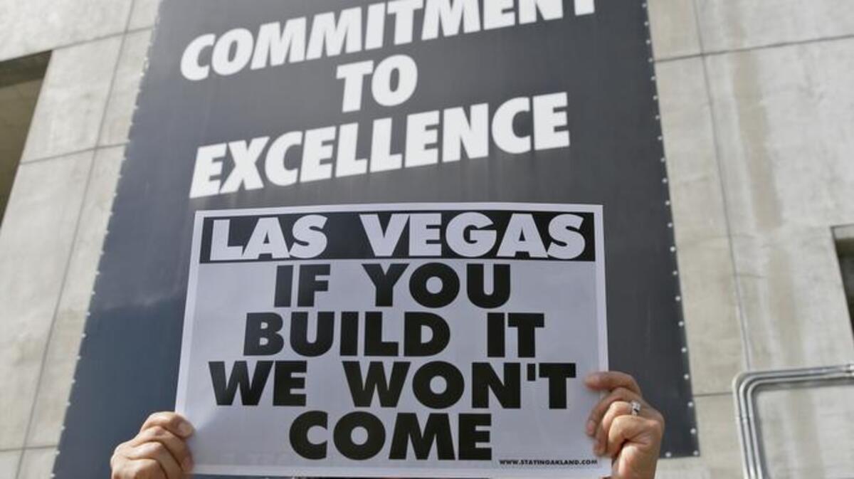 Monette Bonilla of San Jose holds up a sign outside the Oakland Coliseum before the start of a Saturday rally to keep the Oakland Raiders from moving. But NFL owners meeting in Phoenix approved the team’s relocation to Las Vegas this week.