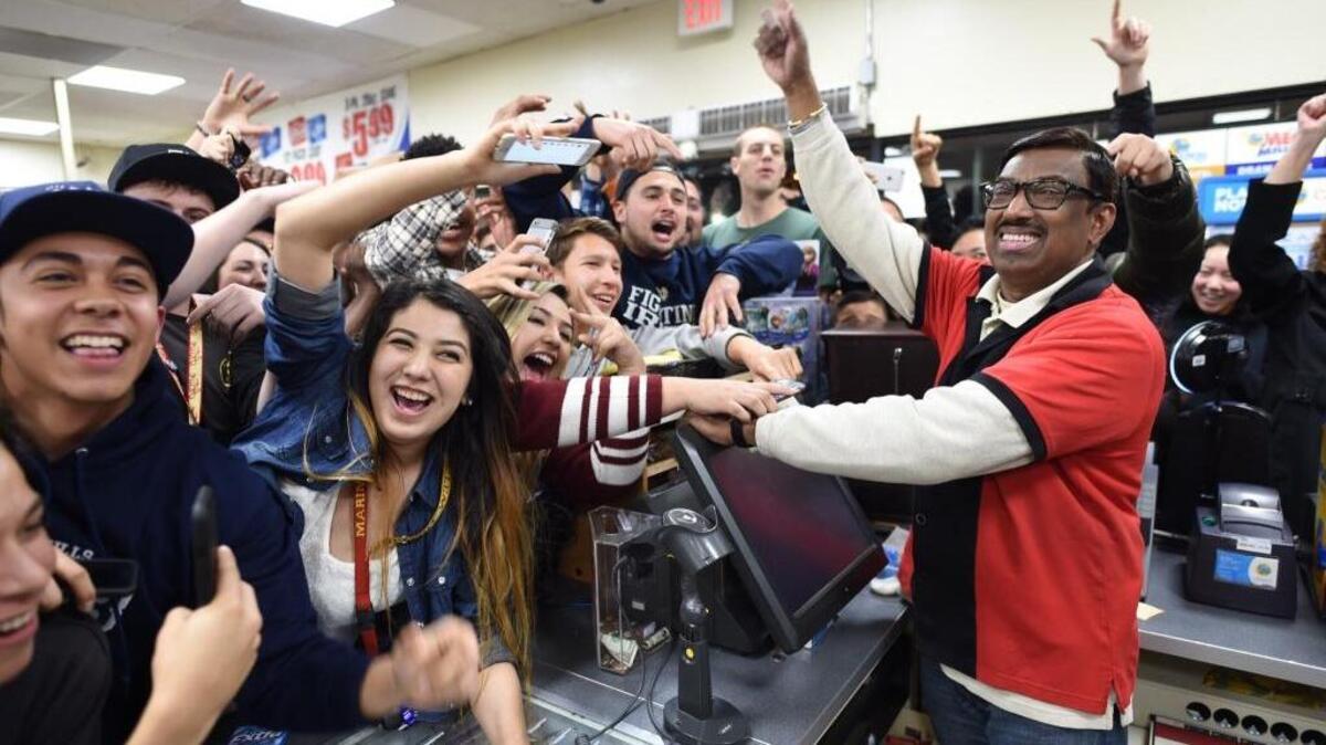 7-Eleven store clerk M. Faroqui celebrates with customers after learning the Chino Hills store sold a winning Powerball ticket.