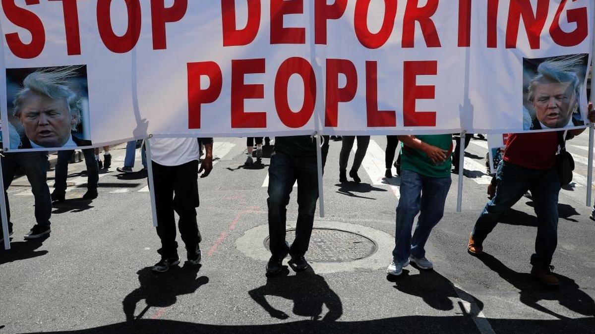 Protesters cast shadows as they walk with a sign during a May Day rally in Los Angeles.