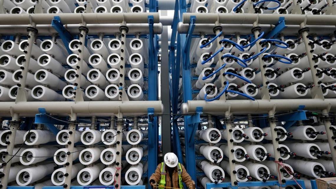 A worker in this 2015 file photo climbs among some of the 2,000 pressure vessels used to convert seawater into fresh water through reverse osmosis in the desalination plant in Carlsbad. The developers of that plant have been awaiting approval for a second plant in Huntington Beach for nearly 20 years.