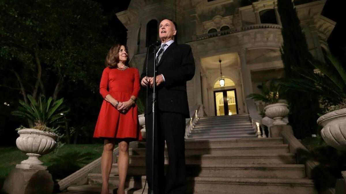 Gov. Jerry Brown and his wife, Anne Gust Brown, greet reporters outside the old Governor’s Mansion. The Browns and their two dogs will move into the mansion after renovations are completed.
