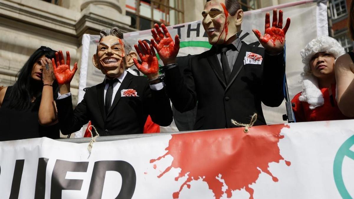 Protesters wearing masks of former British Prime Minister Tony Blair, left, and former President George W. Bush show bloody hands before the release of an official report on the Iraq war in London on Wednesday.