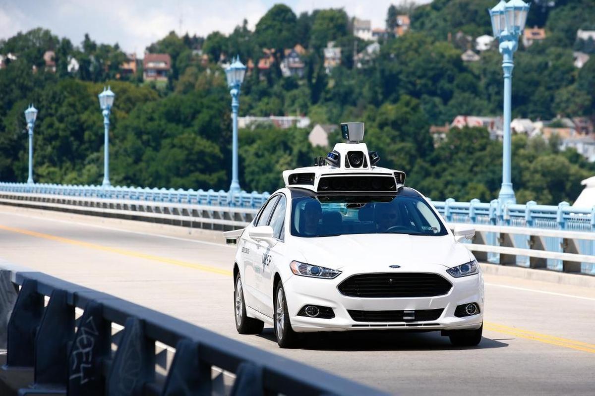 Uber employees test a self-driving Ford Fusion hybrid car in Pittsburgh.