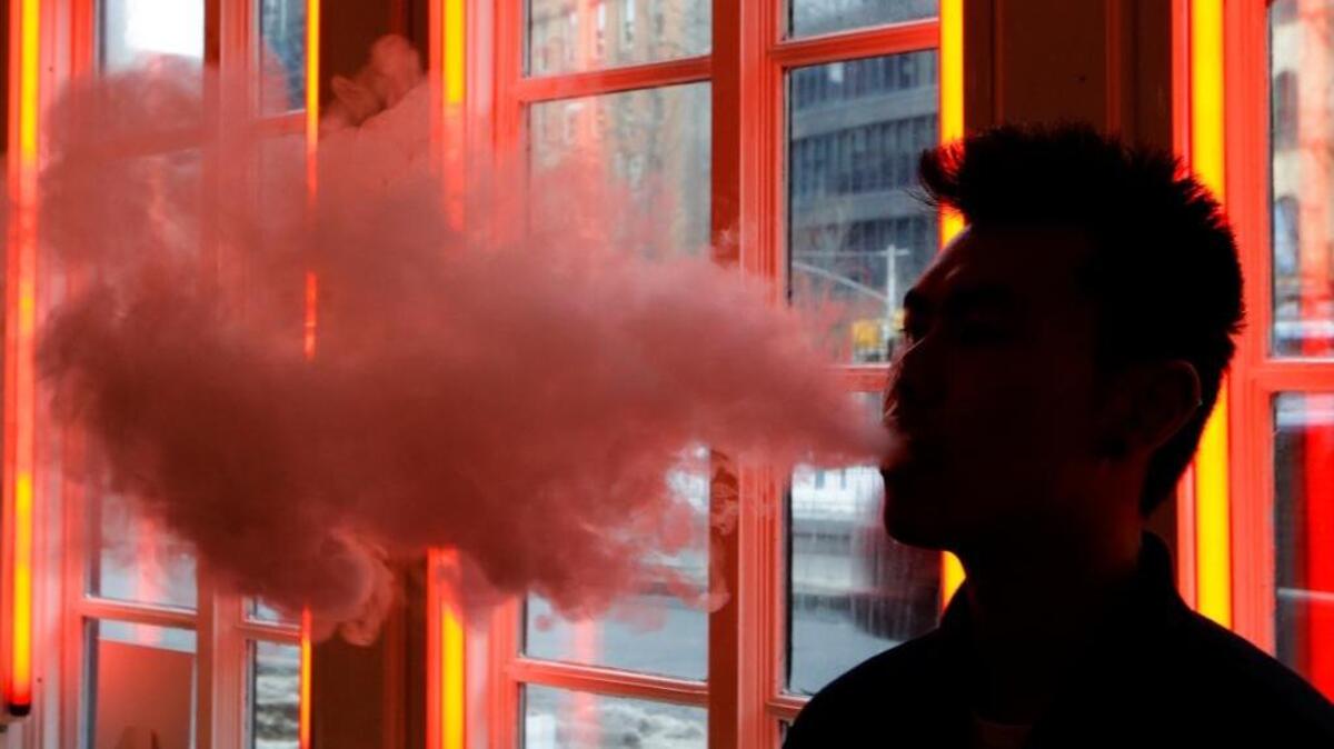 
A man exhales a cloud of vapor from an electronic cigarette. A new study confirms teens who smoke e-cigs are more likely to try regular cigarettes. 
