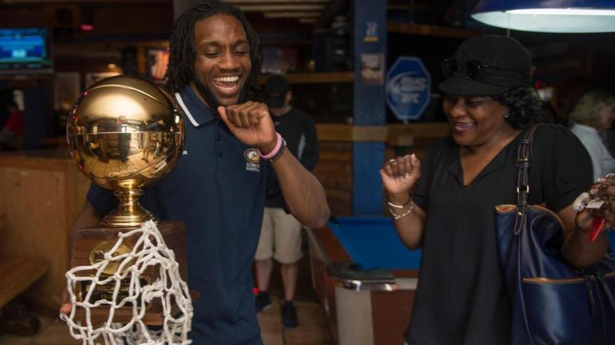 UC Davis senior guard Darius Graham, left, does a victory dance while holding the Big West tournament trophy as the NCAA tournament brackets are announced Sunday.