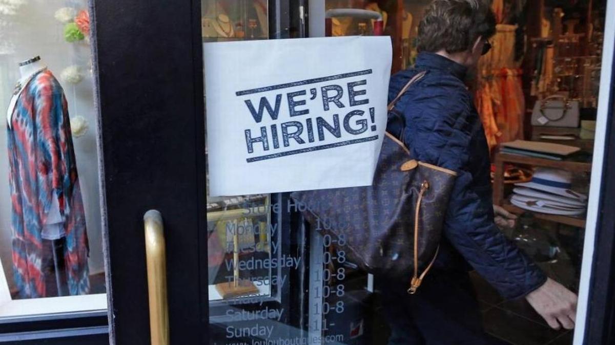 A woman passes a “we’re hiring” sign while entering a Boston clothing store in May. Census data released Tuesday showed middle class incomes rising for the first time since the recession ended in 2009.