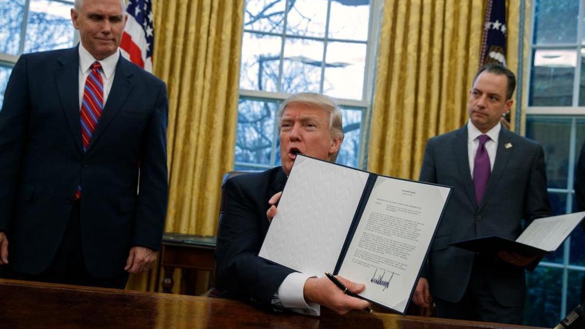 President Donald Trump shows his executive order on Monday withdrawing from the Trans-Pacific Partnership.