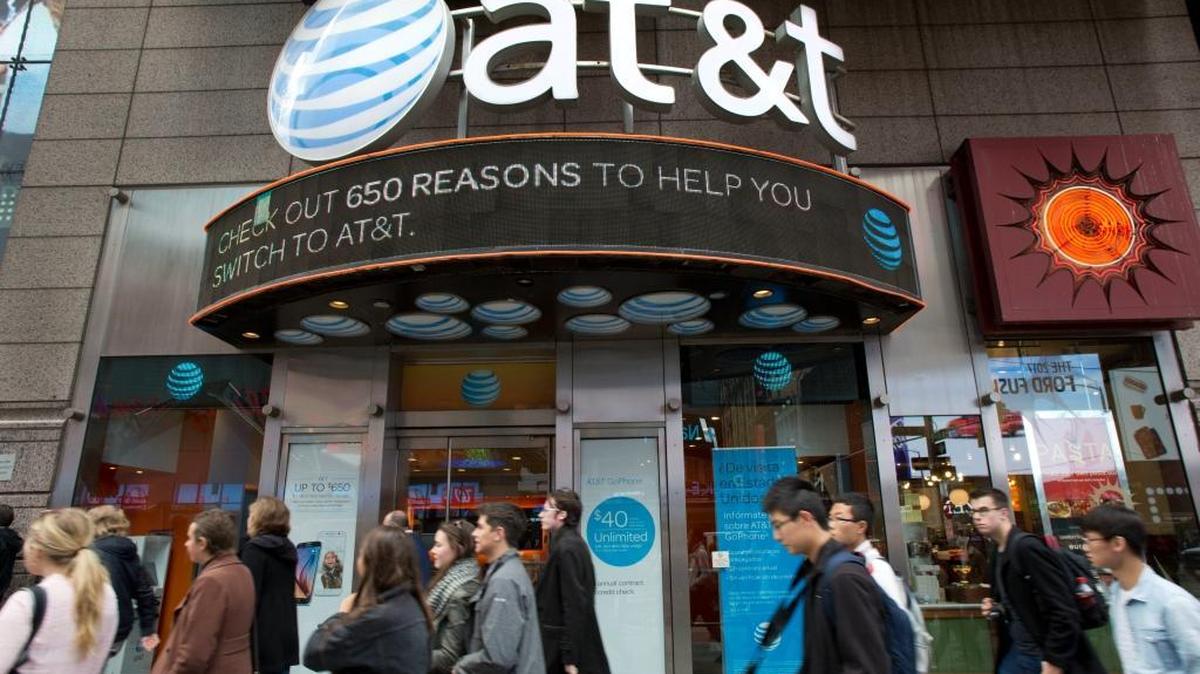 People walk by an AT&T retail store Monday in New York. AT&T plans to buy Time Warner for $85.4 billion.