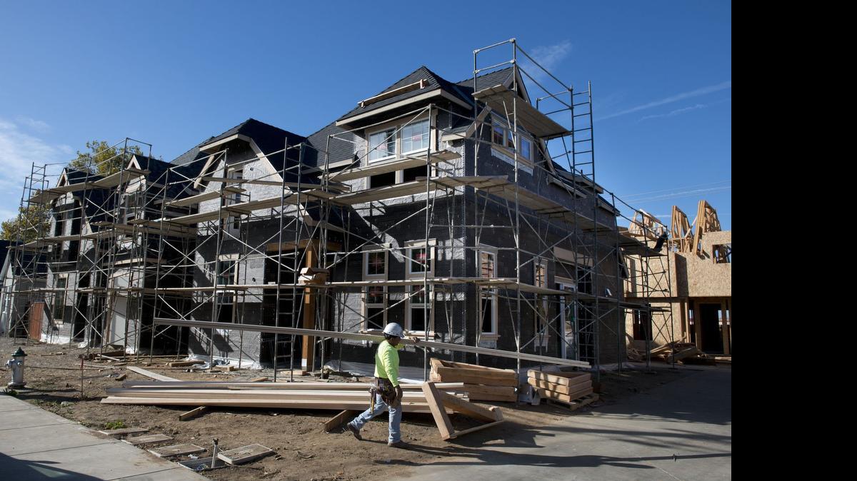 
A construction worker carries lumber outside new cottages being built in Curtis Park Village last October. The planning commission debates a proposed fuel center on Thursday. 
