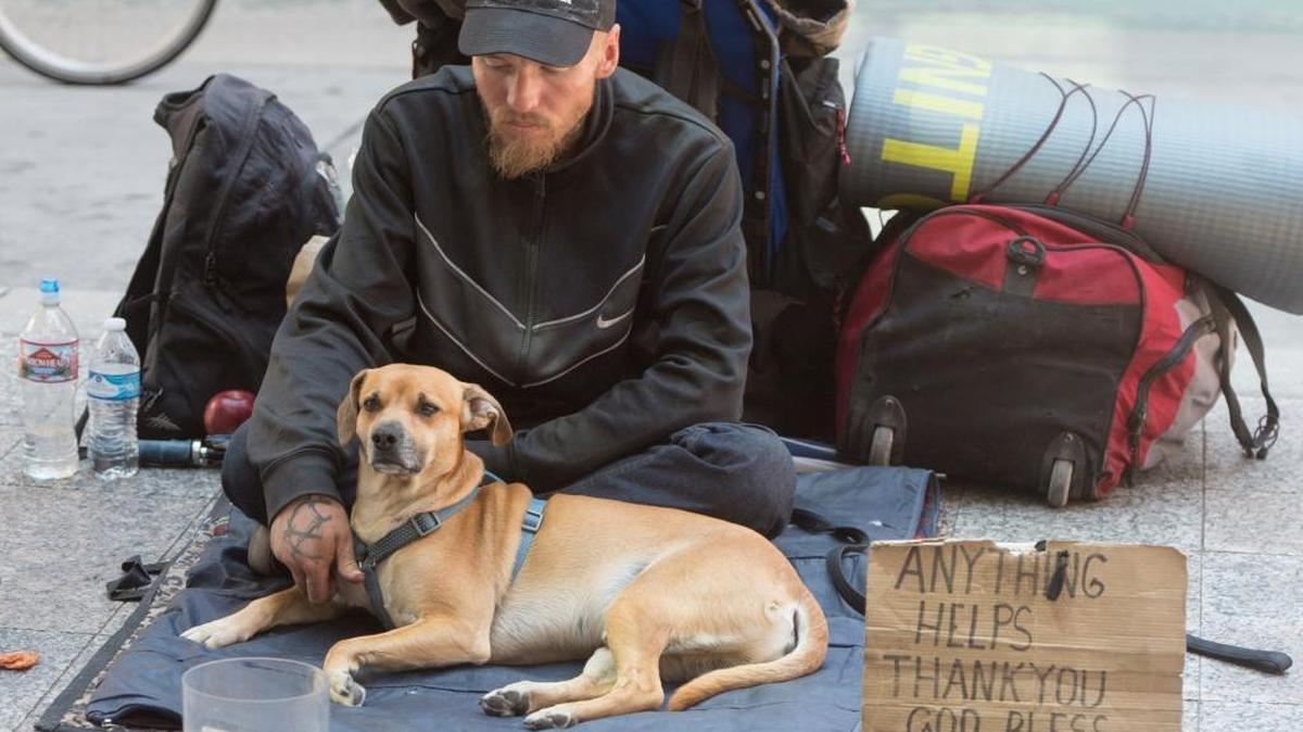 A man and his dog sit on the sidewalk in Salt Lake City. In an effort to discourage panhandling, the city recently put up billboards urging people to give money to organizations that help homeless people instead. Sacramento is considering a more direct approach, banning aggressive begging outright near ATMs and intersections.