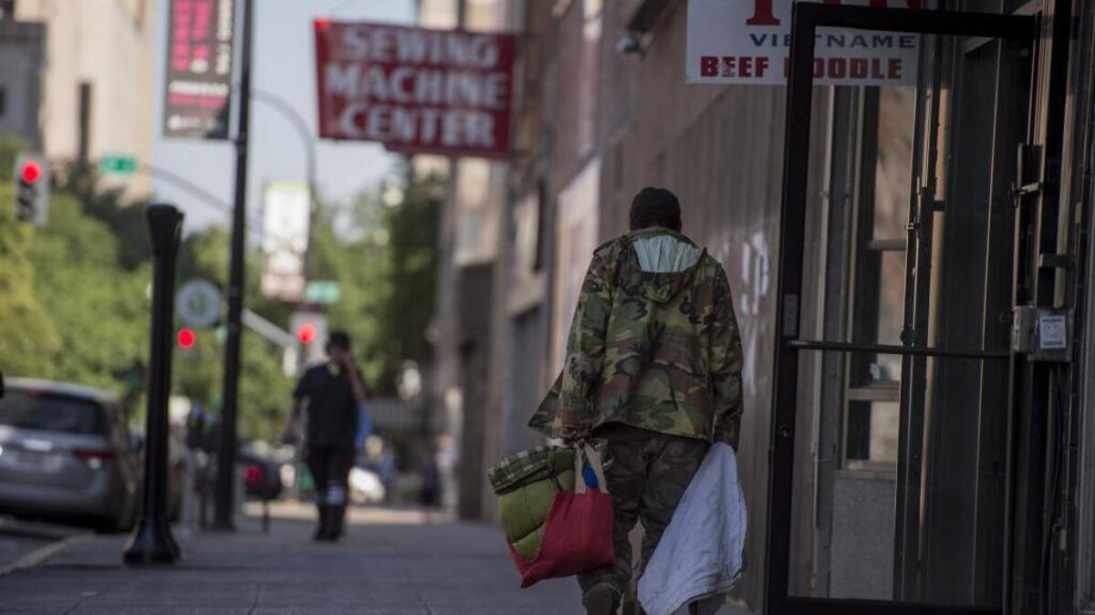 A homeless man walks down J Street between 10th and 11th streets on Monday afternoon in Sacramento. Despite pockets of renewal in other parts of downtown, several buildings on this block still sit vacant.