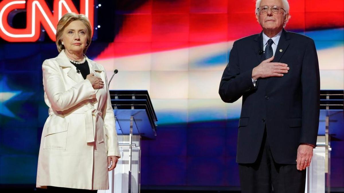 Sen. Bernie Sanders and Hillary Clinton get set for the national anthem at the CNN Democratic presidential primary debate Thursday in New York. When asked, both said they thought the 1994 crime bill was good for the country at the time.
