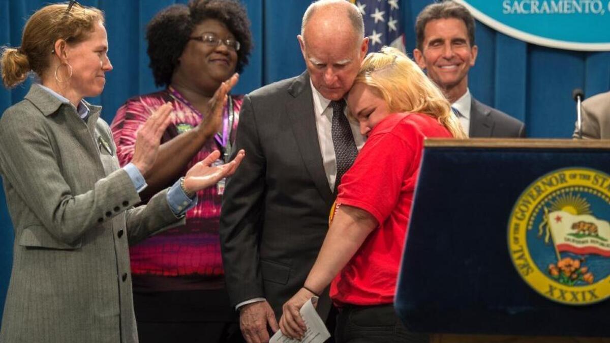 Gov. Jerry Brown, center, hugs emotional Burger King employee Holly Diaz, 38, of Sacramento on Monday.