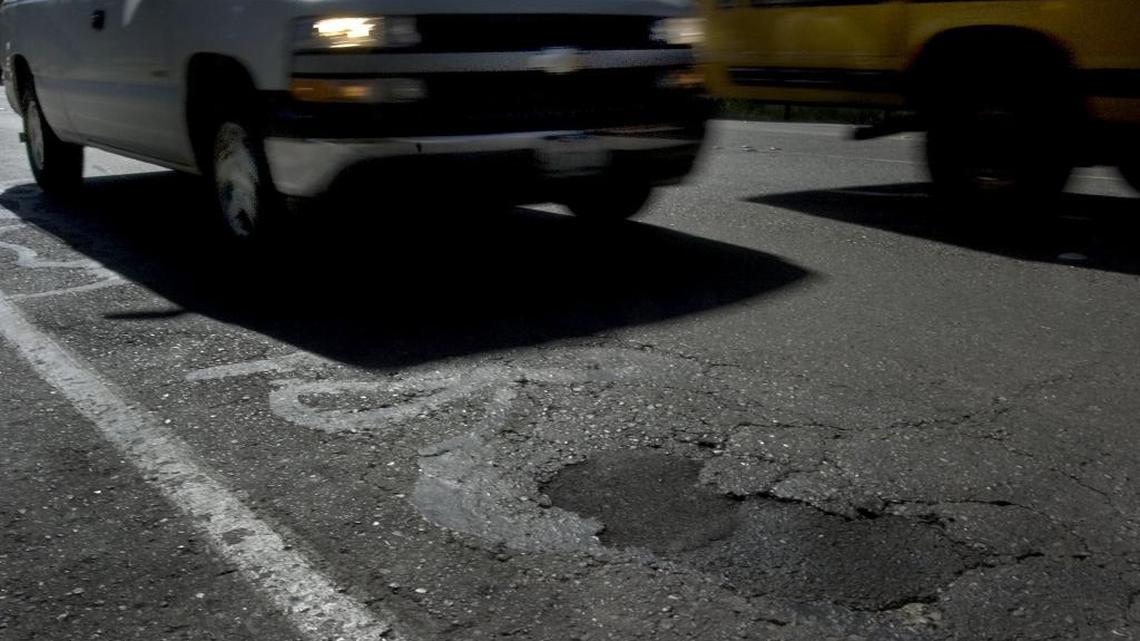 Vehicles drive through potholes and cracks along Auburn Boulevard in Sacramento.