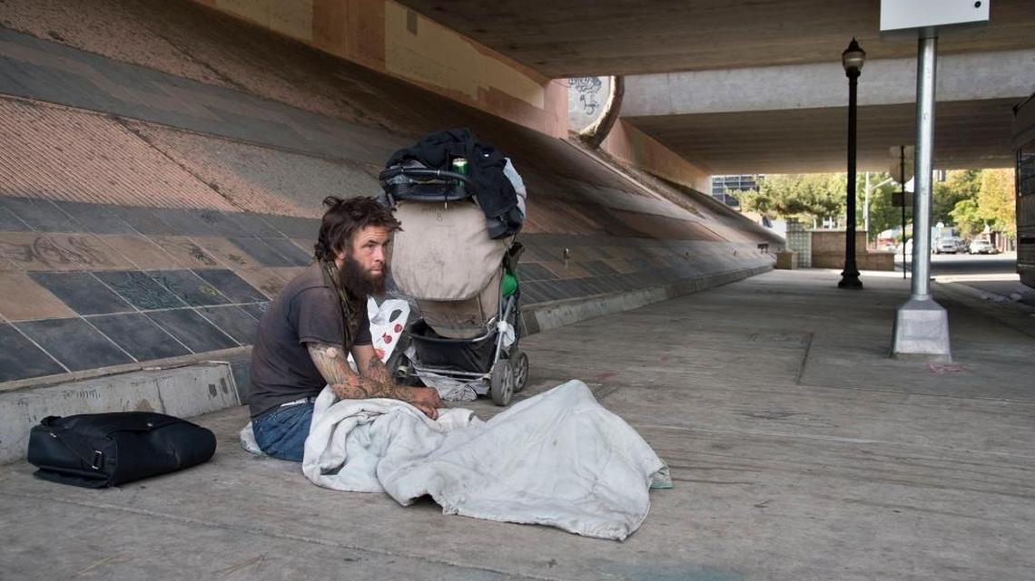 A homeless my who gave his name only as Scott, sits with his belongings under the freeway near 16th and W streets.