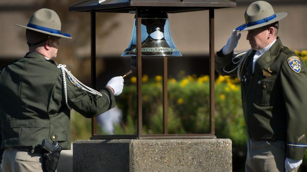 CHP Officer Shawn Ranney, with Officer Brian Samms saluting, rings a bell in a ceremony paying tribute to Officer Nathan Taylor at the CHP Academy in West Sacramento on Wednesday, March 15, 2016.