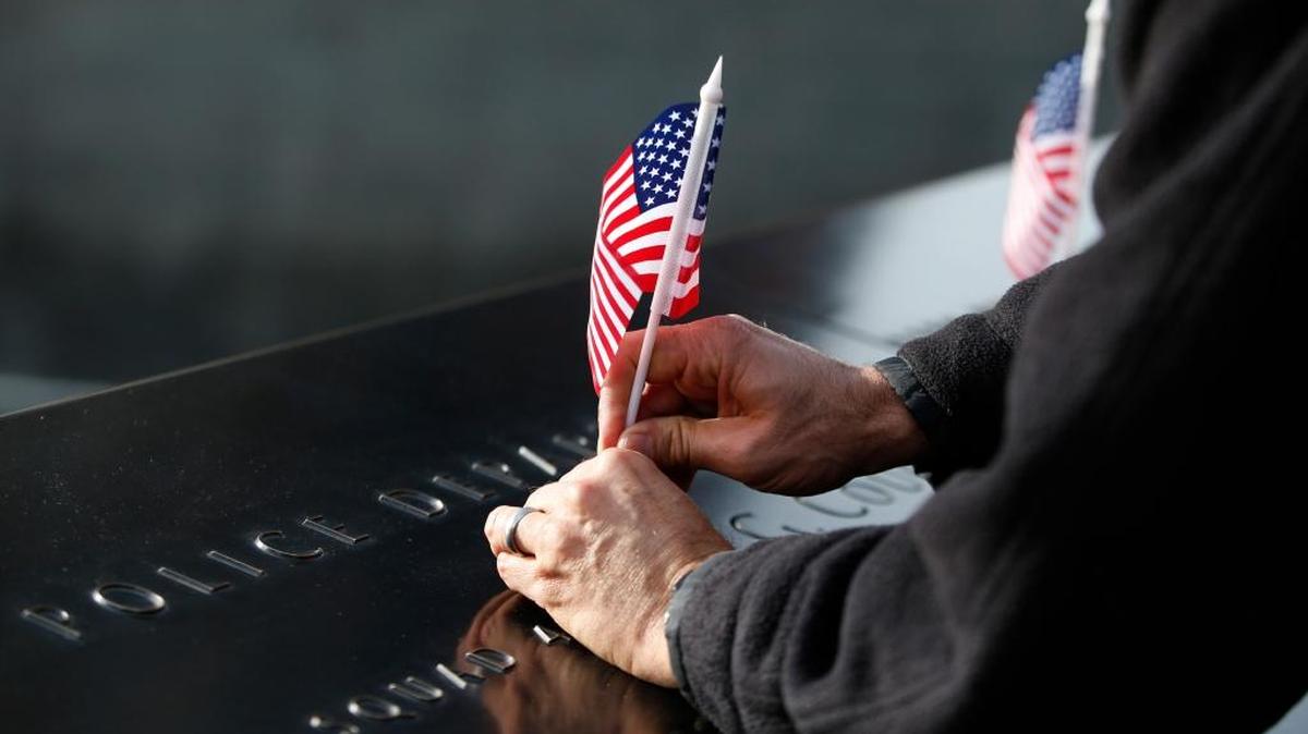 A man adjusts a flag following a ceremony honoring 9/11 first responders who were military veterans. The ceremony was held in advance of Veterans Day