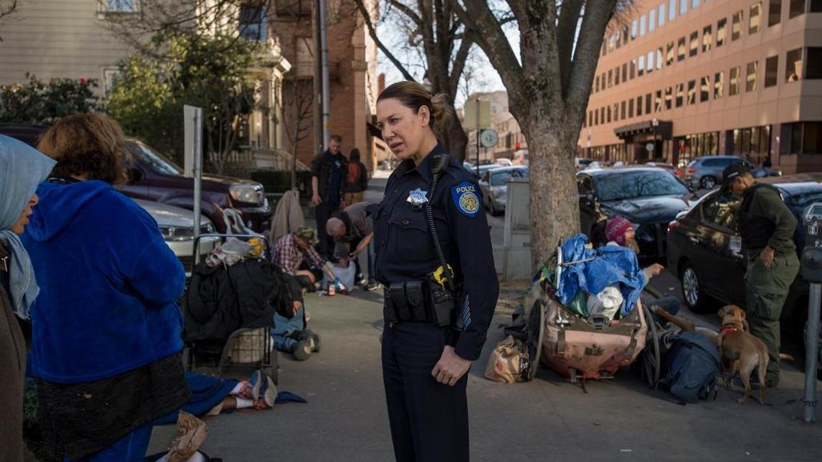 Sacramento police Officer Michelle Lazark talks with homeless people a block from City Hall near the intersection of 11th and I Street, responding to a complaint the sidewalk path was blocked.