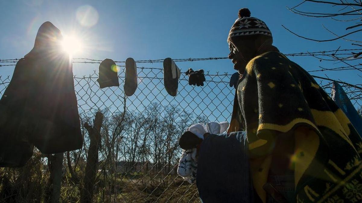 Roland Richie, 62, hangs wet clothing and bedding along a fence on the American River Parkway in December. The recent rain and flooding has been hard on homeless people.