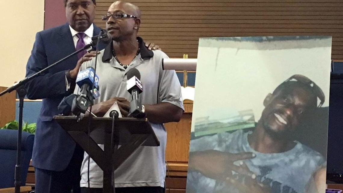 Robert Mann Sr., right, addresses community members and reporters with his attorney, John Burris. Joseph Mann, displayed at right in a photo, was killed by Sacramento police in July.