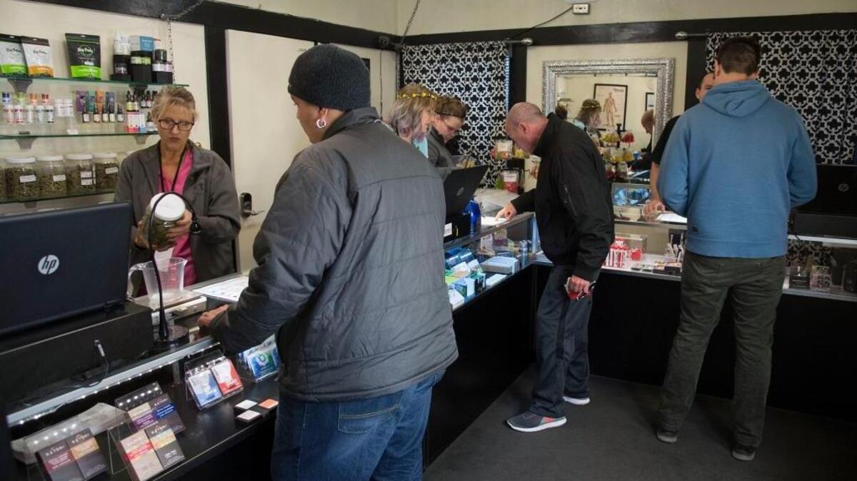 Customers line the retail counter to purchase cannabis at A Therapeutic Alternative in Sacramento.