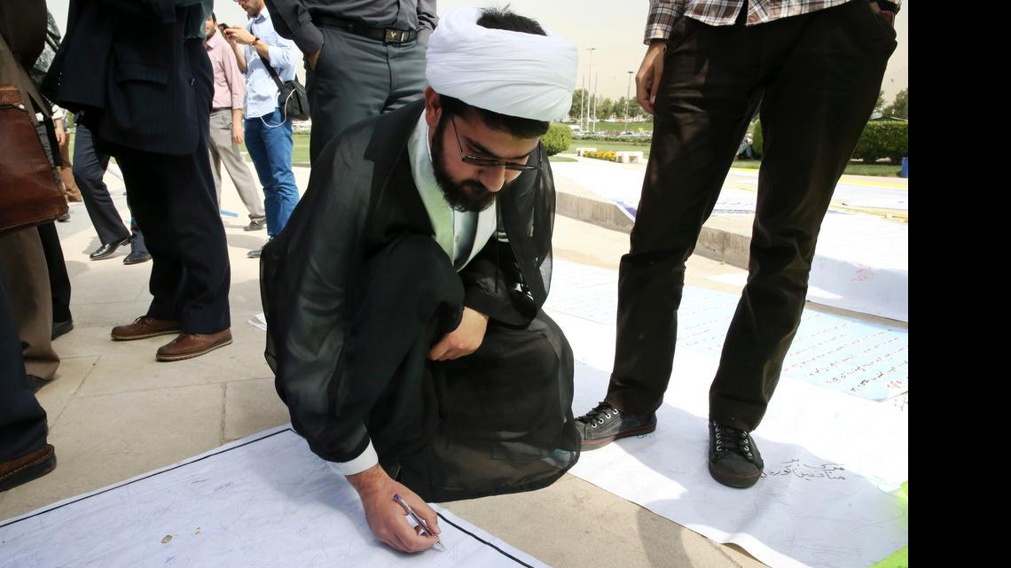 
An Iranian clergyman signs a petition scroll Tuesday during a demonstration in Tehran by a group of hard-liners seeking to reject any inspections of military sites as part of a nuclear deal. 
