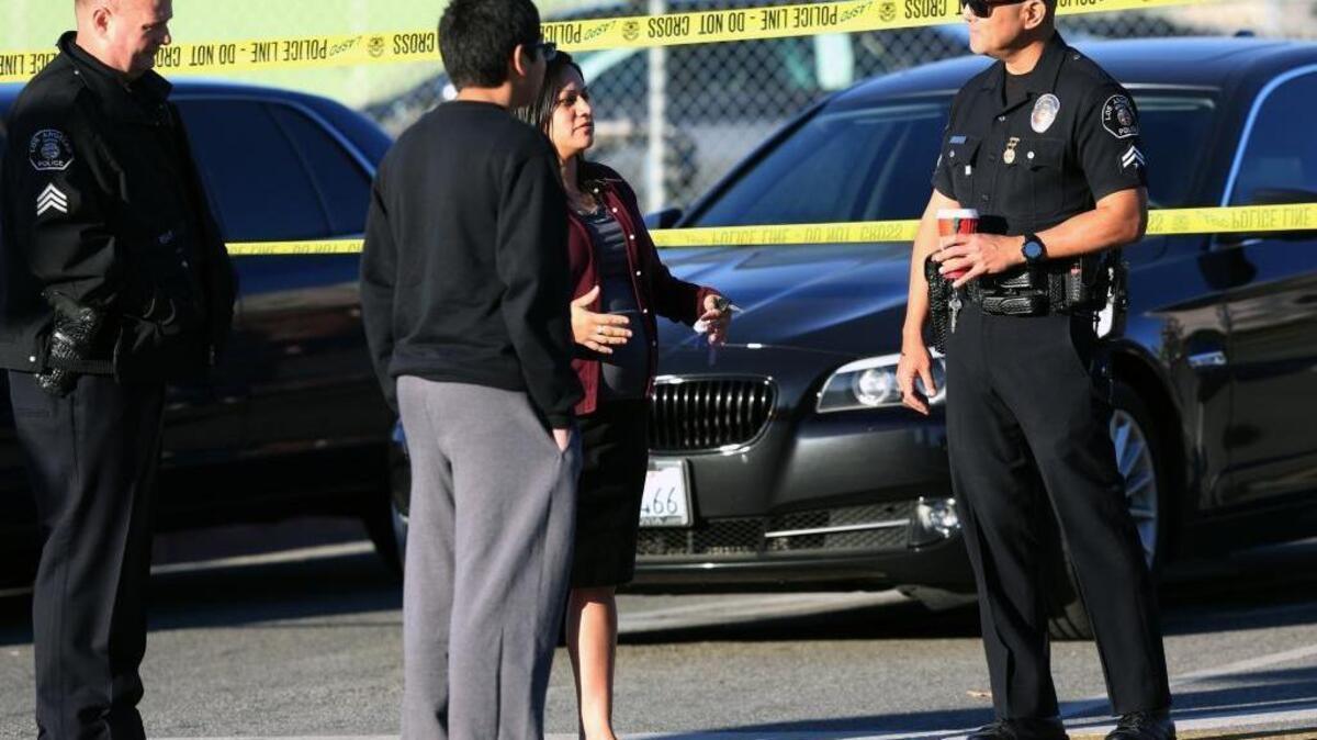 Police officers explain to a parent and her son that officials closed all Los Angeles schools Tuesday after an email threat.