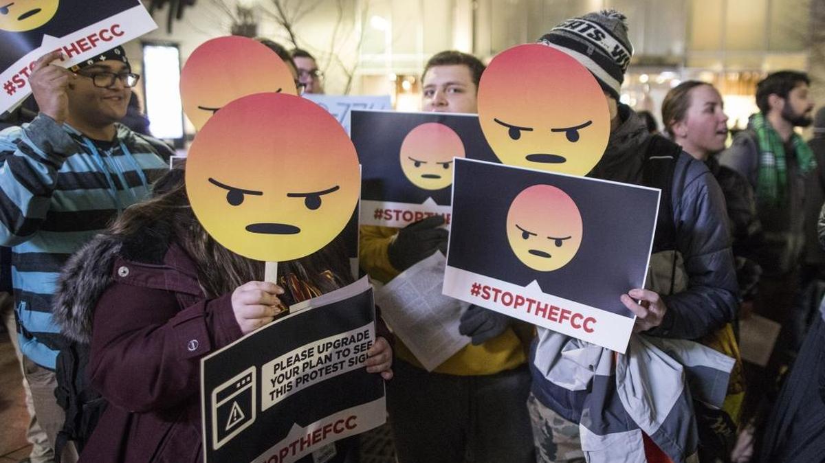 Demonstrators hold up angry-face emojis during a protest of plans to do away with net neutrality regulations.