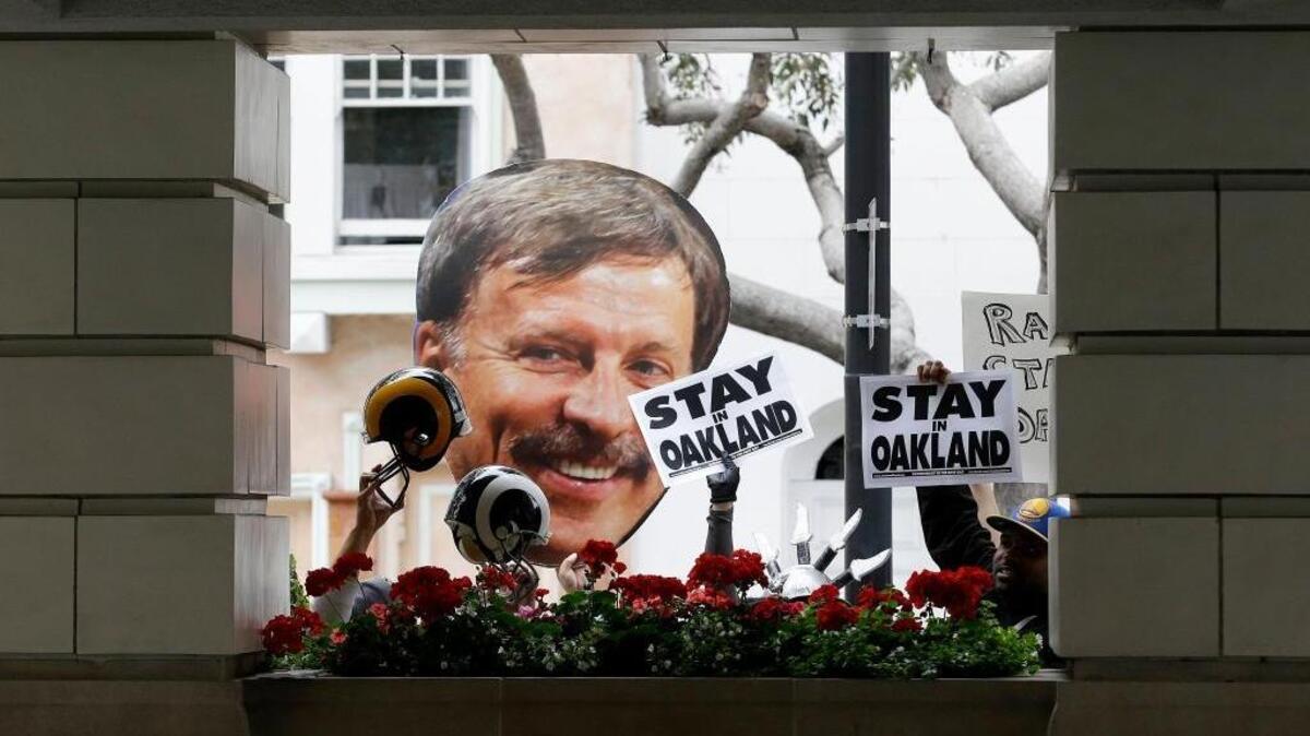 Fans hold up a photo of St. Louis Rams owner Stan Kroenke during a rally with San Diego Chargers and Oakland Raiders fans in San Francisco.